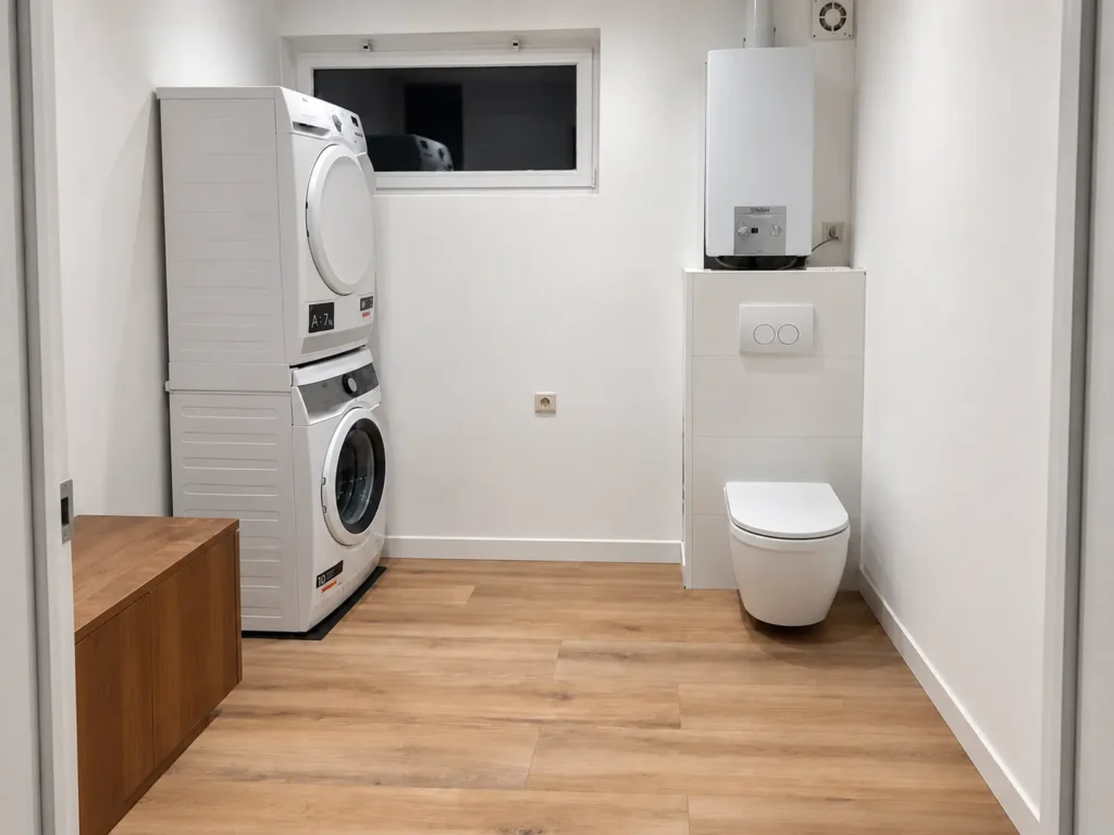 Sanitaire ruimte met wasmachine, droogkast en wandtoilet